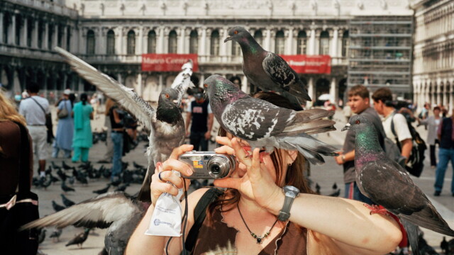 ITALY. Venice. A tourist takes a picture while pigeons surround her. 2005.